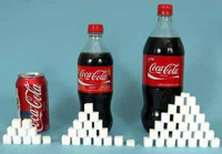 Staplade sockerbitar framför flaskor med Coca cola Staplade sockerbitar framför flaskor med Coca cola